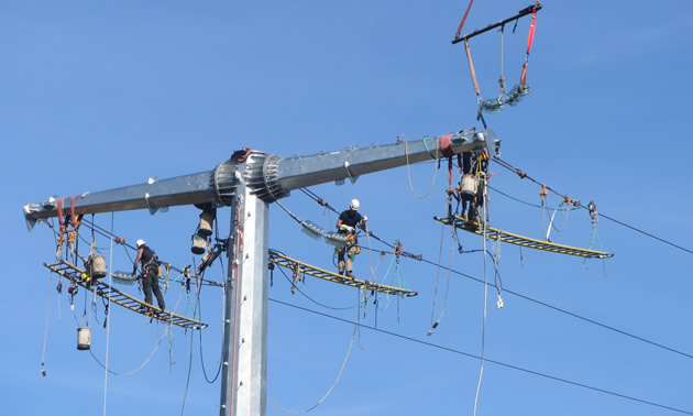 A crew is installing dead-end assemblies on the transmission lines high in the air.