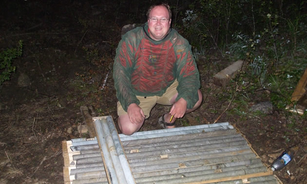 A man kneeling in front of cylindrical core samples of rock
