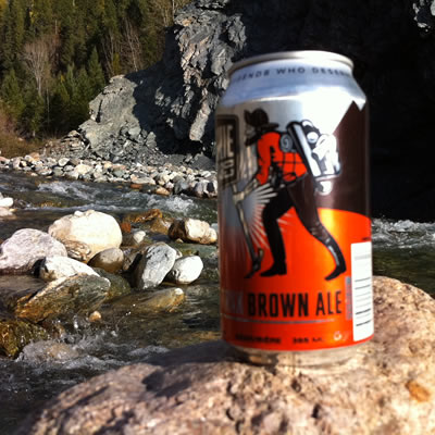 A beer can with a picture of a prospector on it, with a river in the background. 