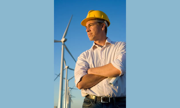 man wearing hardhat standing near wind turbines